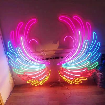 Des ailes d'ange et un panneau au néon décorant une fête avec des lettres de marquise